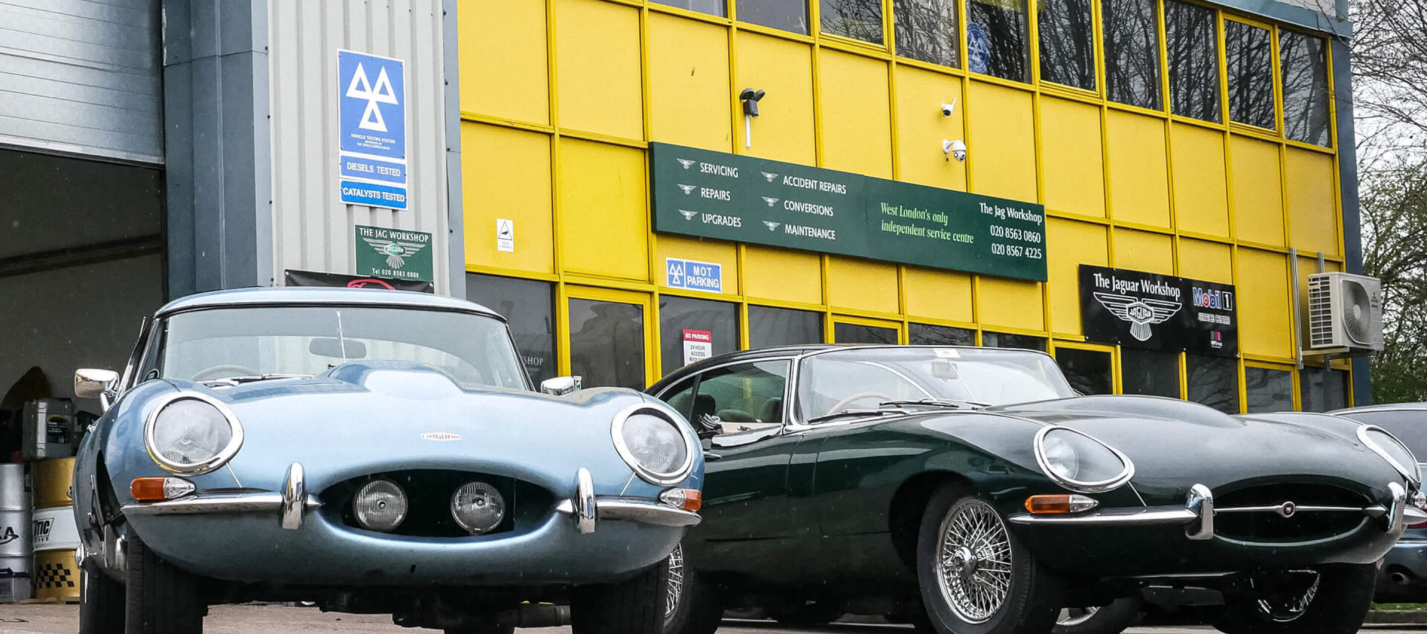 Front entrance of The Jag Workshop with two Jaguar E-Types outside. One Blue and the other Dark Green
