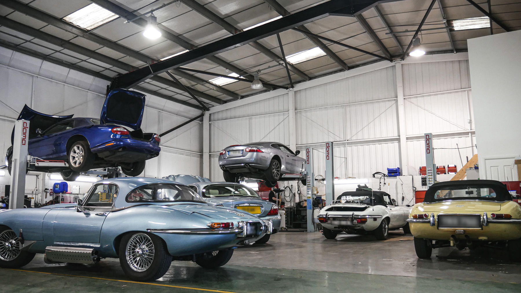 Wide shot of the workshop showing classic and modern Jaguars being repaired  
